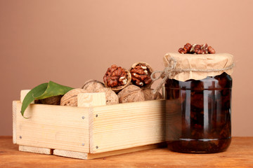 jam-jar of walnuts and  wooden box on brown  background