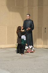 Madre e hijo junto a la estatua de un santo