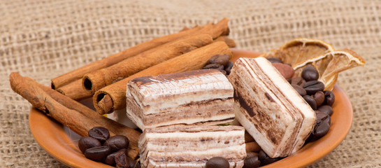 Sweets, cinnamon, nuts and coffee beans on a saucer, on burlap b