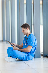 male hospital nurse using tablet computer during break