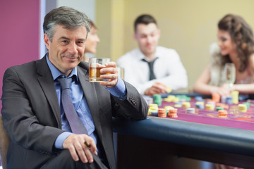 Man drinking whiskey at roulette table