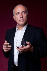 confident senior man with cigar and glass of cognac
