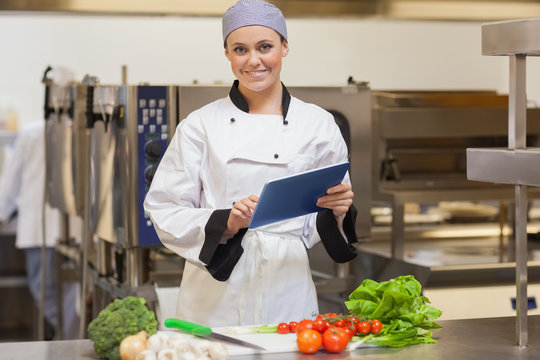 Smiling chef using her digital tablet beside the vegetables - Powered by Adobe