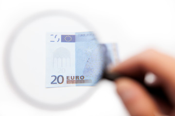 Hand using magnifying glass on euro note