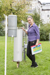 Smiling woman meteorologist inspecting  instruments