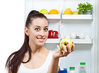 cute girl with apple near the open refrigerator