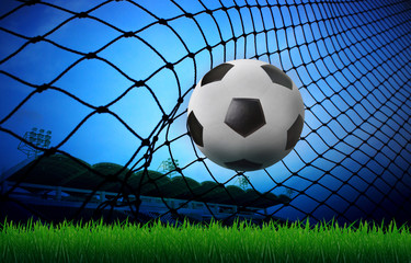 soccer football in goal net and stadium blue sky background
