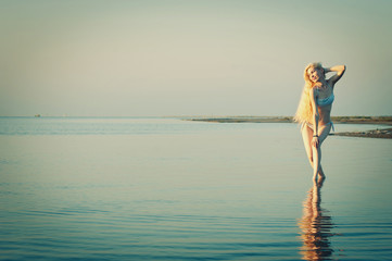 Beautiful young woman posing at the beach at sunset.