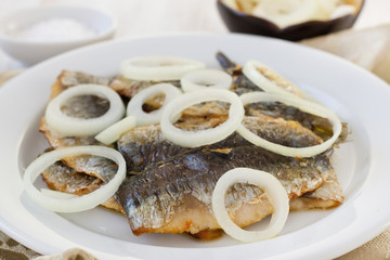 fried filet of sardines with onion on the plate