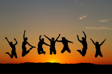 silhouette of friends jumping in sunset