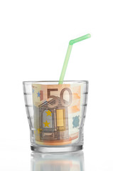 Financial concept: drinking a 50 euro bill in a glass and a stra