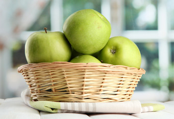Ripe green apples with leaves in basket,