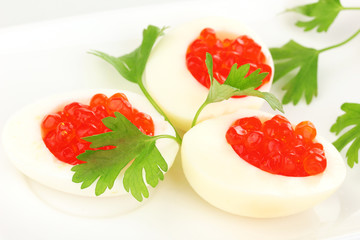 Red caviar in eggs on white plate close-up