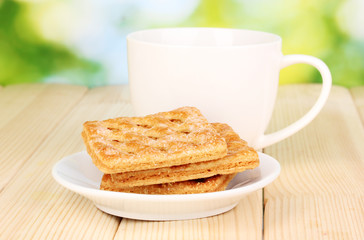 Cup of tea and cookies on wooden table on bright background