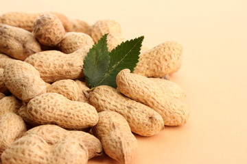 tasty peanuts with green leaves, on beige background