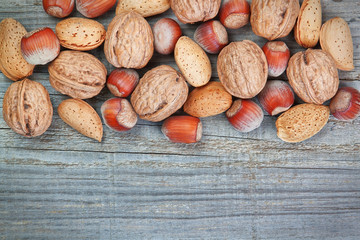 Background of old wooden board and hazelnuts and walnuts.