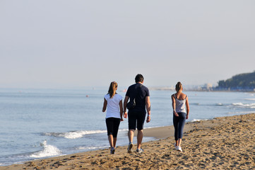Genitore  e figlie adolescenti camminano sulla spiaggia