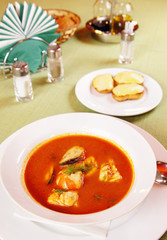 Bouillabaisse - Tomato soup with seafoods on a laid table