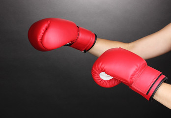 Red boxing gloves on hands on grey background