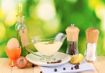 Mayonnaise in bowl on wooden table on nature background