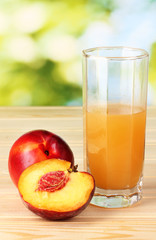 Ripe peaches and juice on wooden table on natural background