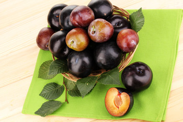 Rip plums on basket on wooden table