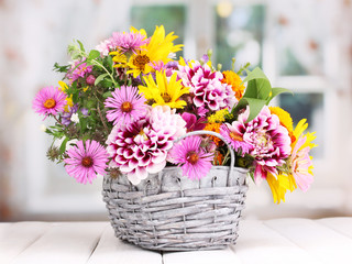 beautiful bouquet of bright flowers in basket on wooden table