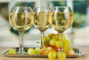 White wine in glass on salver on window background
