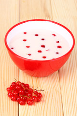 Yogurt with redcurrant on wooden table