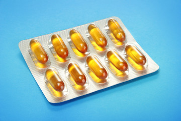 Capsules packed in blisters, on blue background