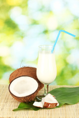 glass of coconut milk and coconuts on green background close-up