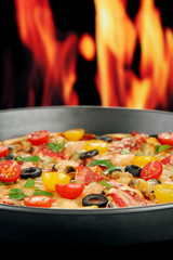 Delicious pizza with seafood on fire background