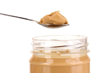 Delicious peanut butter in jar and spoon isolated on white