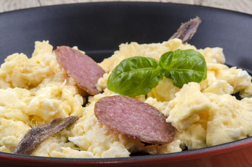 Rührei mit Salami, Sardellen und Basilikum in einer Pfanne