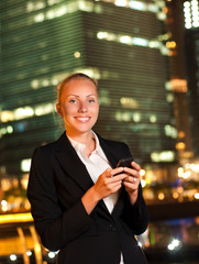 Smiling young business woman with the mobile phone in the big ci
