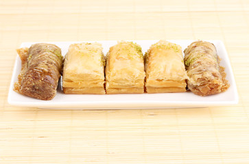 Sweet baklava on plate on bamboo mat