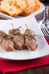 Meat skewers on white dish.