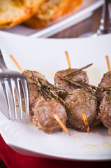 Meat skewers on white dish.