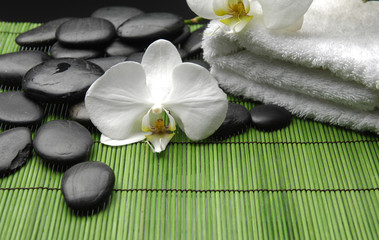 Fototapeta na wymiar White orchid and stones with towel on green mat
