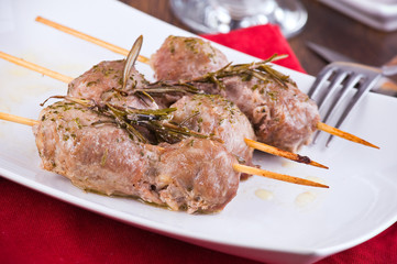 Meat skewers on white dish.
