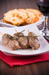 Meat skewers on white dish.