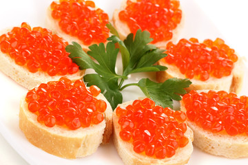 Red caviar on bread on white plate close-up