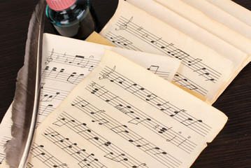 Musical notes and feather on wooden table