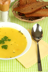 Fragrant soup in white plate on green tablecloth close-up