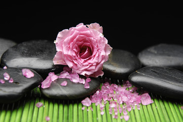 Single pink rose and massage stones in green mat