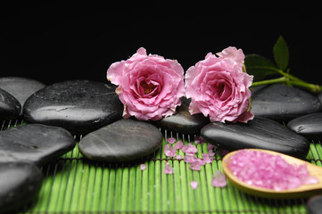 Two rose with herbal salt in spoon with stones on green mat