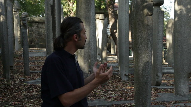 Muslim man praying  friends at graveyard