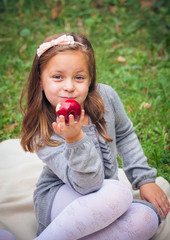 little girl is eating apple outdoor