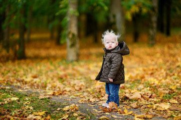 Adorable baby girl having fun on an autumn day