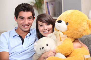 Young couple sat with giant teddy bear